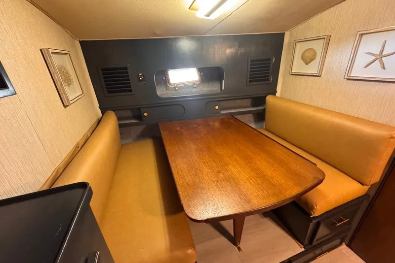Slide: The Image of 1982 Sunliner Ocean Yachts interior with cozy dining area, wooden table, and beige seating. - 36