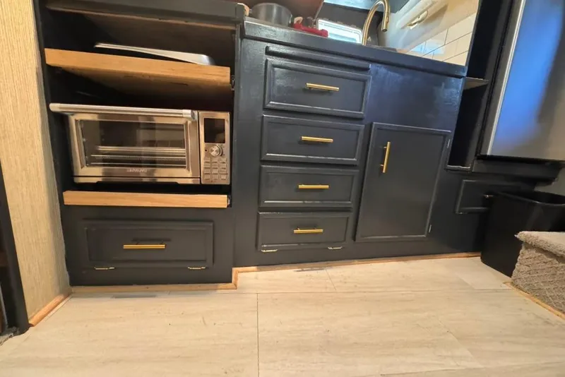 Slide: The Image of 1982 Sunliner Ocean Yachts kitchen with dark cabinets, gold handles, and a compact oven. - 39