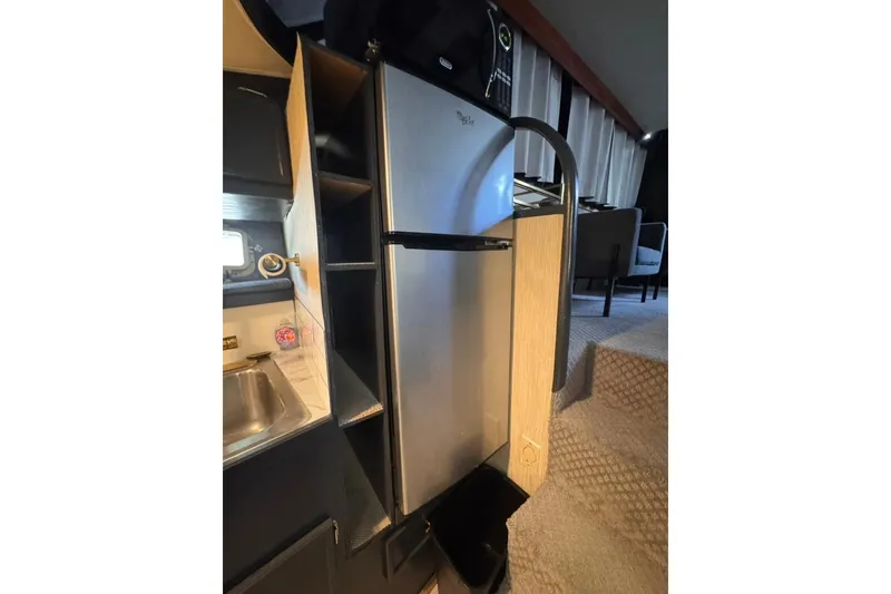 Slide: The Image of Compact kitchen area in a 1982 Sunliner Ocean Yachts, featuring a stainless steel refrigerator. - 42