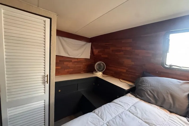 Slide: The Image of Cozy bedroom interior of 1982 Sunliner Ocean Yachts with wood paneling and compact fan. - 43