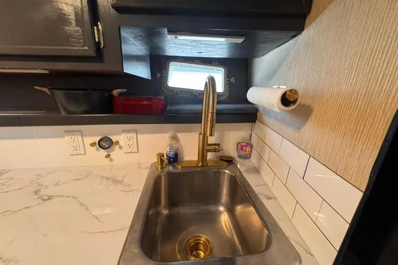 Slide: The Image of Compact yacht kitchen sink with brass faucet, marble countertop, and window in 1982 Sunliner Ocean Yachts. - 44