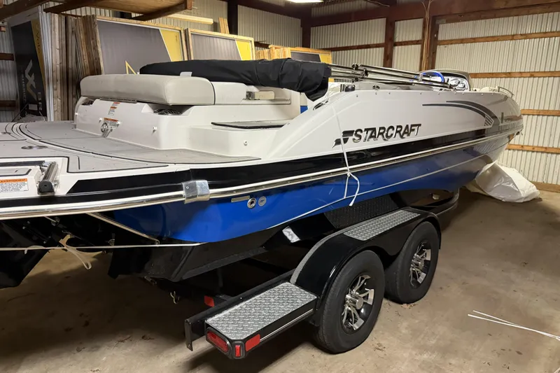 Slide: The Image of 2022 Starcraft Star Step 221 I/O boat in storage, featuring sleek design and dual-axle trailer. - 5