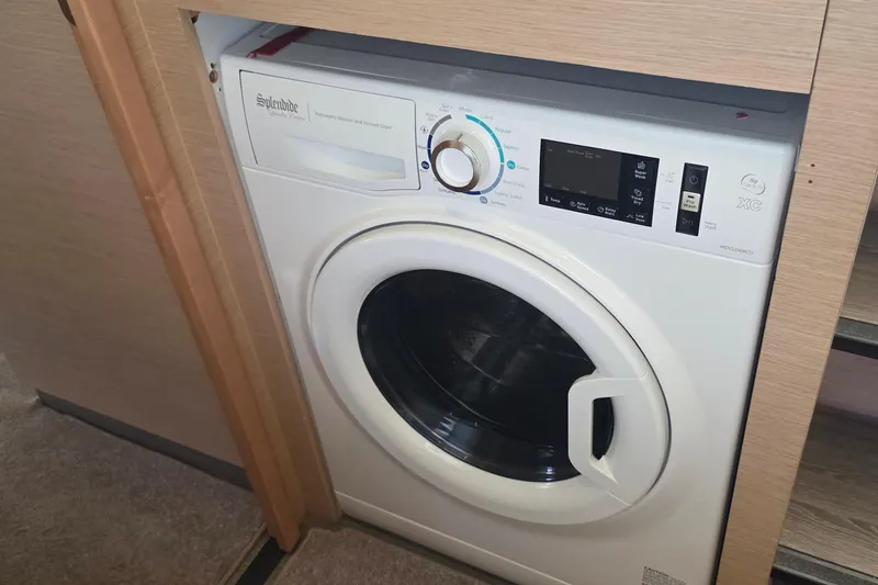 Slide: The Image of Built-in washing machine on 2018 Fountaine Pajot Motor Yacht 44, neatly integrated in wooden cabinetry. - 58