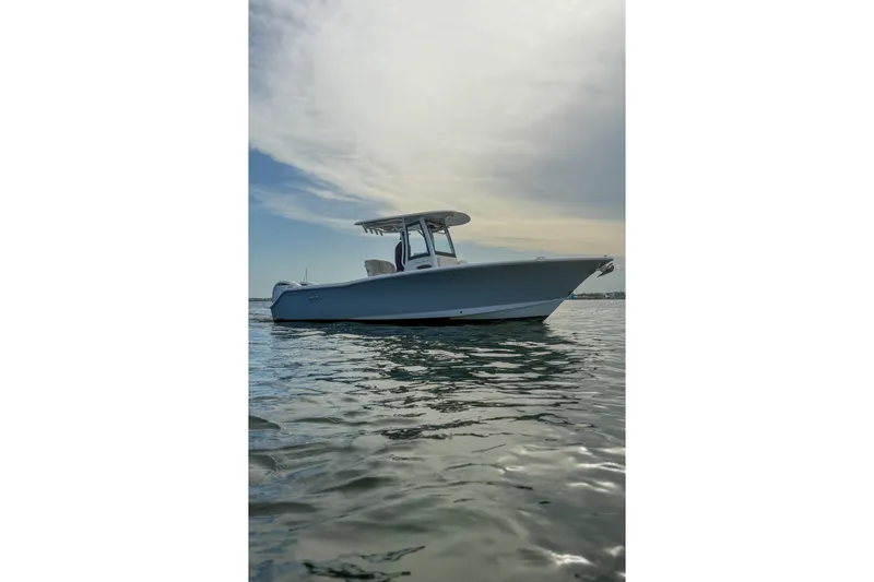 Slide: The Image of 2024 Sea Hunt Gamefish 27 boat on calm water under a cloudy sky. - 9