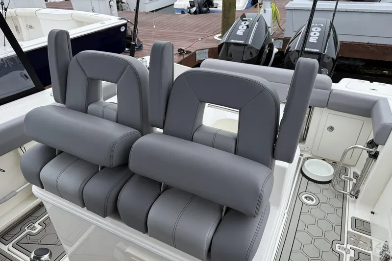 Slide: The Image of 2024 Boston Whaler 280 Outrage boat interior with gray seating and dual outboard engines. - 14