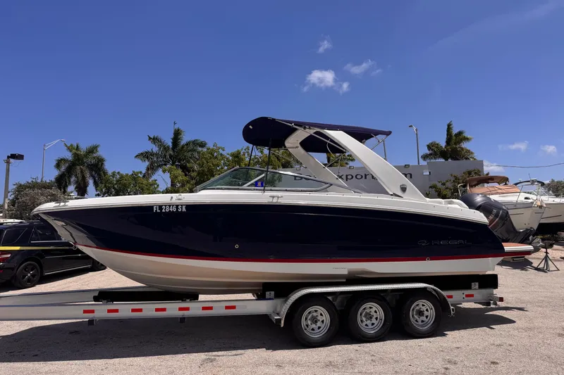 Slide: The Image of 2018 Regal 26 OBX boat on trailer, parked outdoors under clear blue sky. - 2