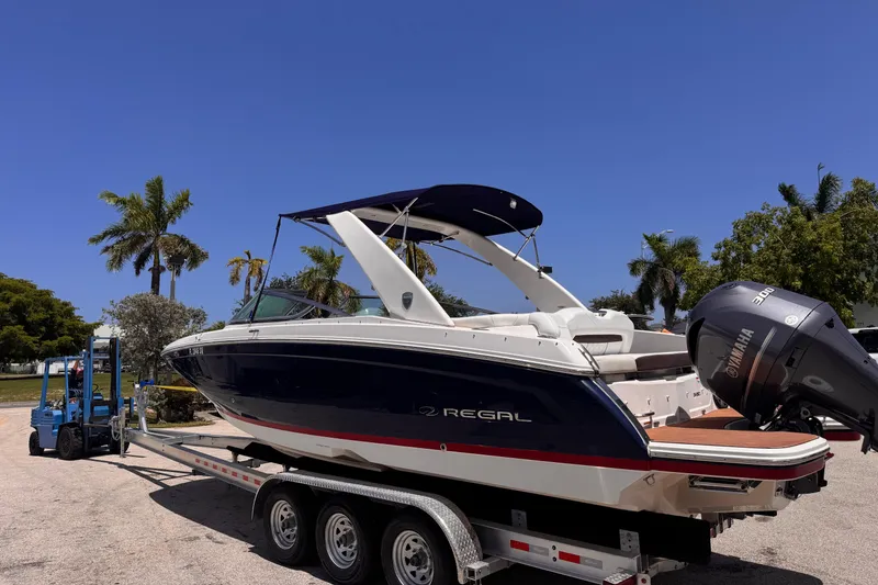 Slide: The Image of 2018 Regal 26 OBX boat on trailer, parked outdoors with palm trees in background. - 3