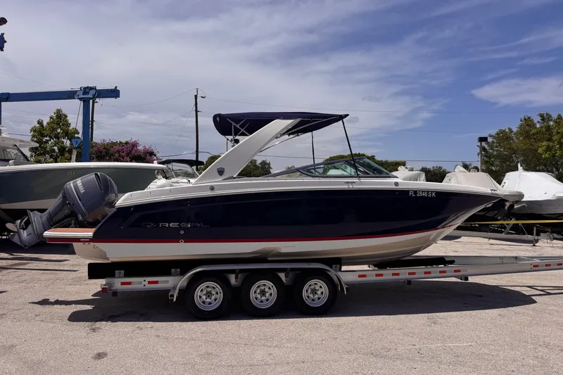 Slide: The Image of 2018 Regal 26 OBX boat on trailer, parked outdoors under a clear sky. - 5