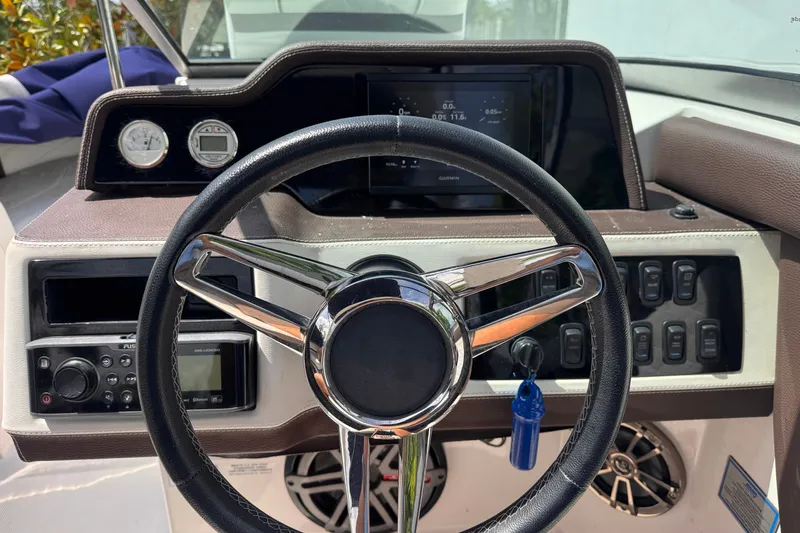 Slide: The Image of Steering wheel and dashboard of a 2018 Regal 26 OBX boat, featuring modern controls. - 13