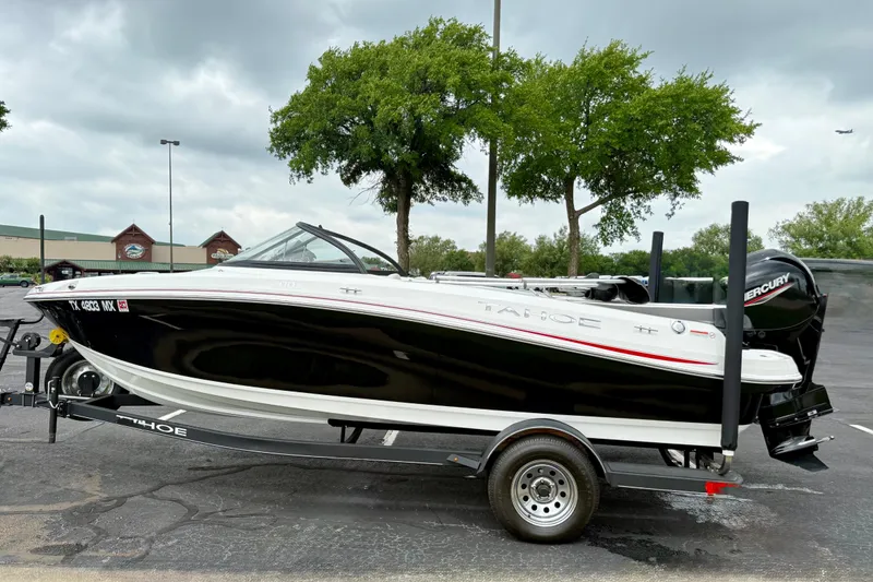 Slide: The Image of 2024 Tahoe 200 S boat on trailer, parked outdoors with trees in the background. - 8