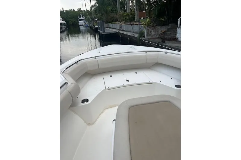 Slide: The Image of 2016 Boston Whaler 270 Dauntless boat interior with white seating, docked near lush greenery. - 6