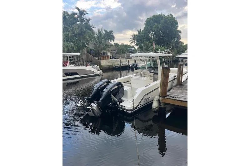 Slide: The Image of 2016 Boston Whaler 270 Dauntless docked by palm trees, featuring dual engines. - 14