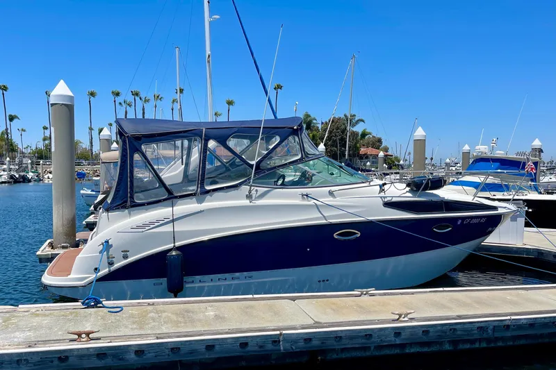 The Image of 2008 Bayliner 265 boat docked at marina, featuring blue and white exterior with canopy. - 0