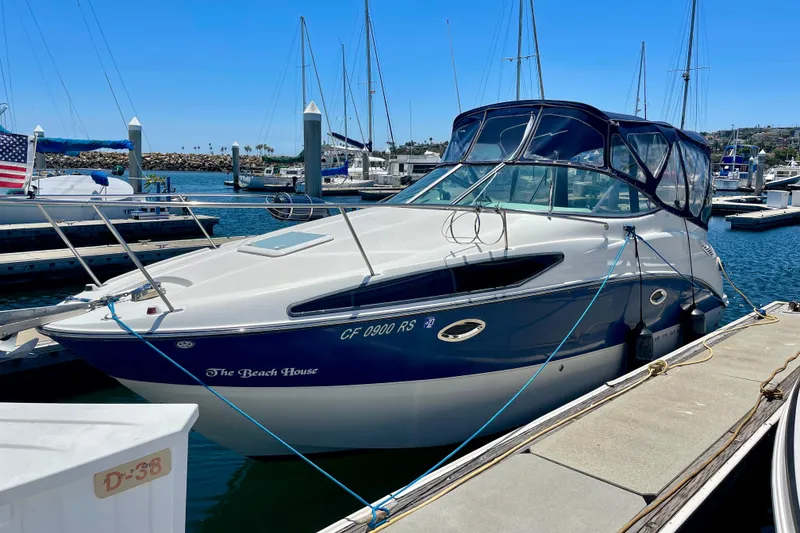 Slide: The Image of 2008 Bayliner 265 boat docked at marina, featuring sleek design and blue accents. - 2