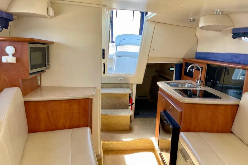Slide: The Image of 2008 Bayliner 265 interior with kitchenette, seating, and stairs to deck. - 20