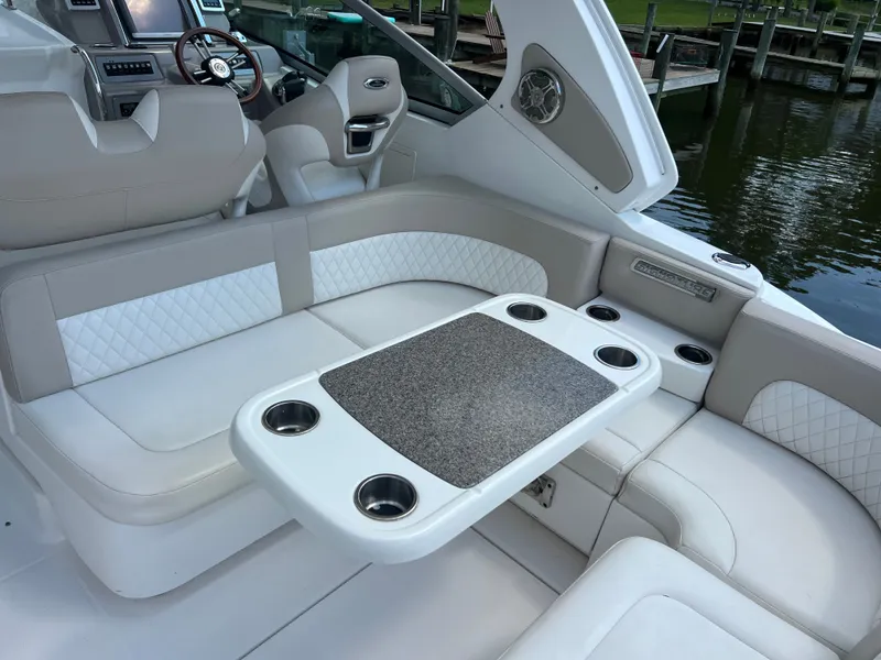 Slide: The Image of The image shows the interior of a 2013 Chaparral 330 Signature boat with beige seating and a table. - 20