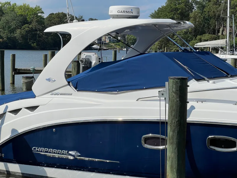 Slide: The Image of A 2013 Chaparral 330 Signature boat docked, featuring a blue cover. - 37