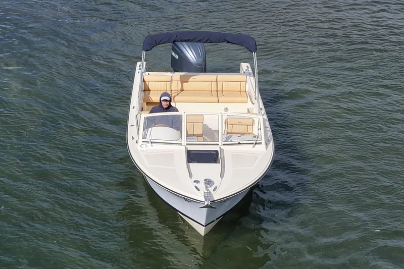 Slide: The Image of 2027 Rossiter 23 Closed Deck boat cruising on water, featuring beige seating and a canopy. - 11