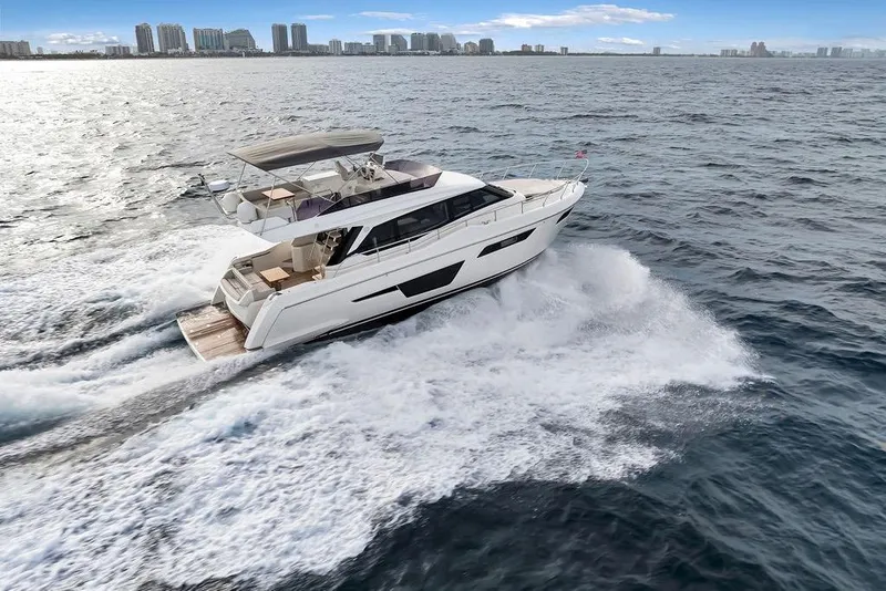 Slide: The Image of 2021 Ferretti Yachts 500 cruising on open water with city skyline in background. - 6