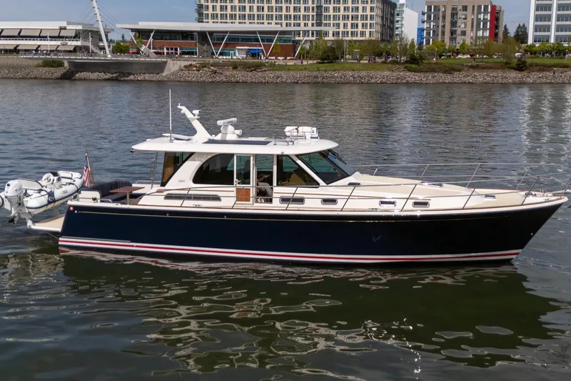 Slide: The Image of 2023 Sabre 45 Salon Express yacht on calm water, urban skyline in background. - 1