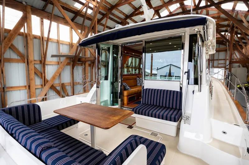 Slide: The Image of 2023 Sabre 45 Salon Express yacht interior with striped seating and wooden table. - 12