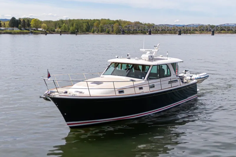 Slide: The Image of 2023 Sabre 45 Salon Express yacht cruising on a calm river with scenic background. - 3