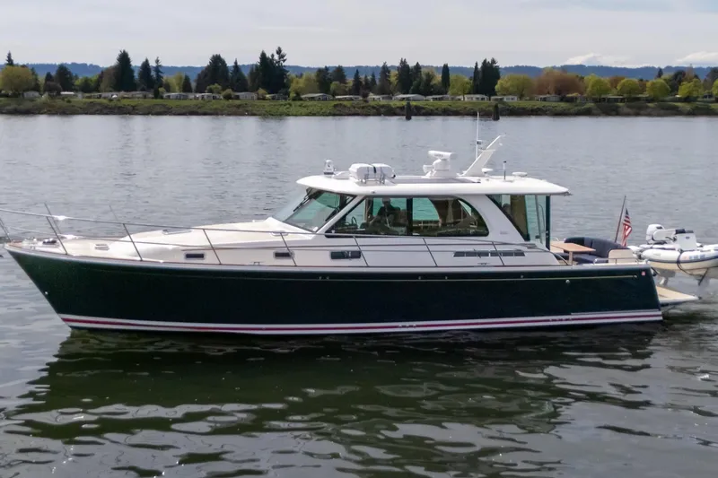 Slide: The Image of 2023 Sabre 45 Salon Express yacht cruising on a calm river with scenic background. - 4