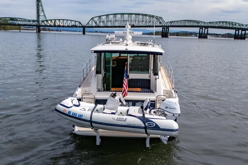 Slide: The Image of 2023 Sabre 45 Salon Express yacht with dinghy, cruising near a bridge on a calm river. - 5