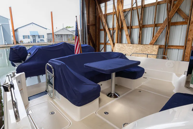 Slide: The Image of 2023 Sabre 45 Salon Express yacht interior with blue-covered seating and table in a marina setting. - 9