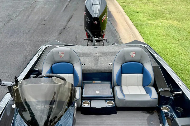 Slide: The Image of 2023 Triton 18 TrX boat interior with dual seats and motor, parked on pavement. - 9