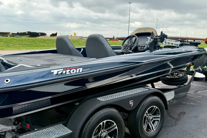 Slide: The Image of 2023 Triton 18 TrX boat on trailer, sleek design, parked outdoors under cloudy sky. - 2