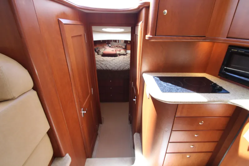 Slide: The Image of Interior of 2006 Silverton 38 Sport Bridge, featuring wood cabinetry and compact kitchen area. - 13