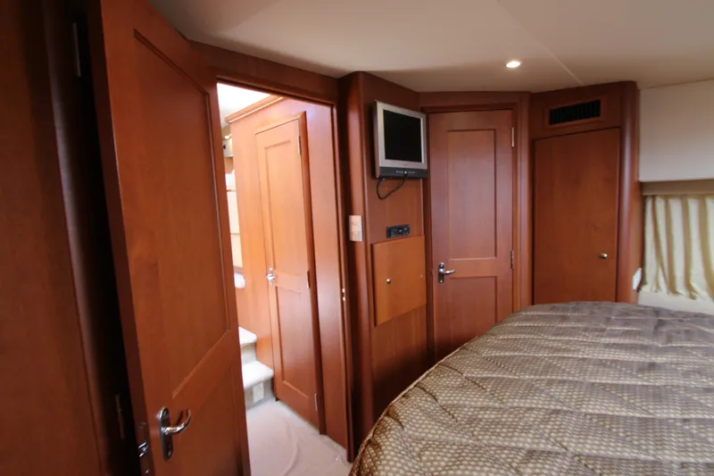 Slide: The Image of Interior of 2006 Silverton 38 Sport Bridge yacht with wood paneling and cozy bedroom. - 17