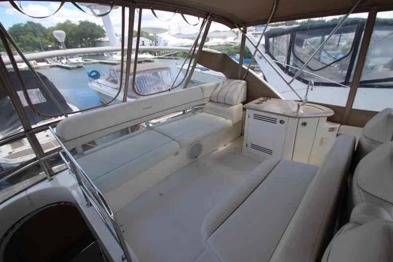 Slide: The Image of 2006 Silverton 38 Sport Bridge interior with plush seating and kitchenette, docked at marina. - 40