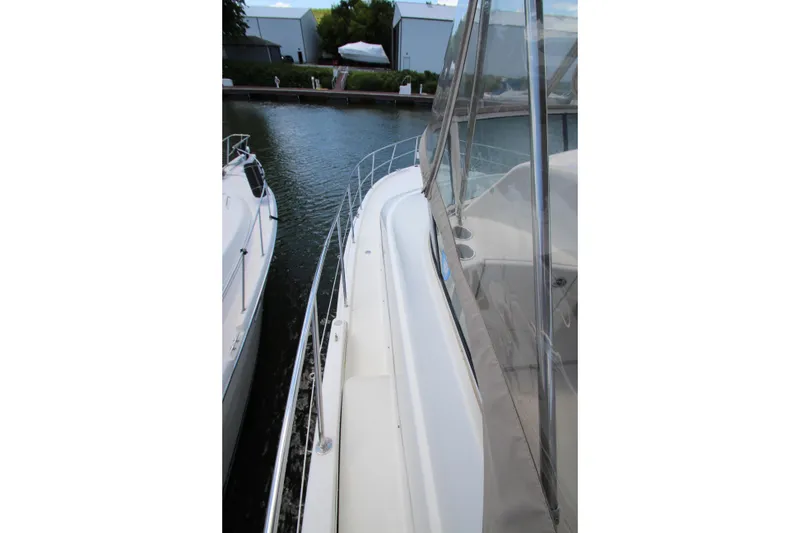 Slide: The Image of 2006 Silverton 38 Sport Bridge yacht docked, showcasing sleek design and spacious deck area. - 48