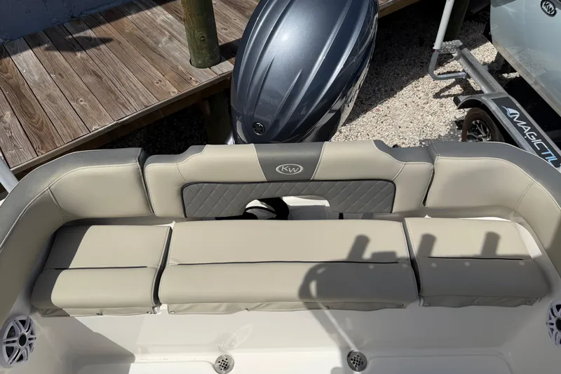 Slide: The Image of 2026 Key West 203 FS boat seating with outboard motor, docked on gravel. - 10