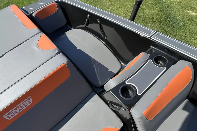 Slide: The Image of 2018 Heyday WT-2 boat interior with gray and orange seating, cup holders, and logo. - 17