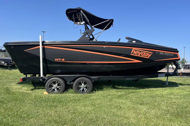 Slide: The Image of 2018 Heyday WT-2 boat on trailer, black with orange accents, parked on grass. - 3