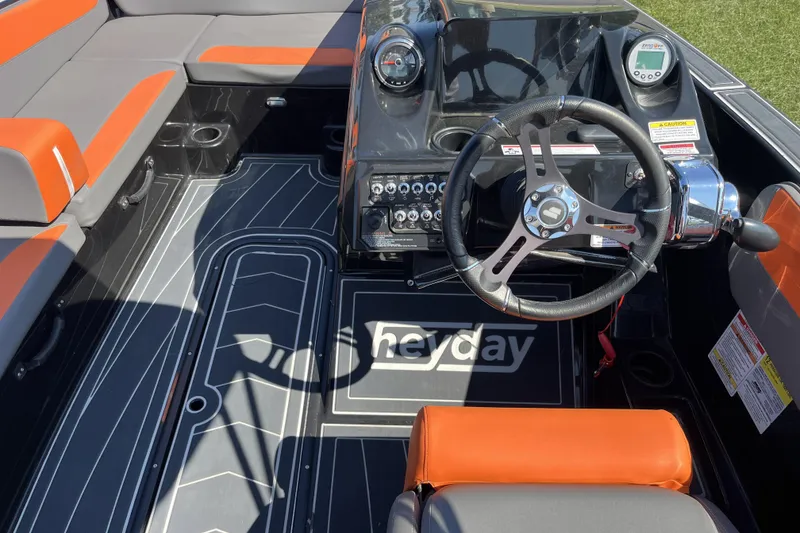 Slide: The Image of 2018 Heyday WT-2 boat interior with steering wheel, dashboard, and orange-gray seating. - 12