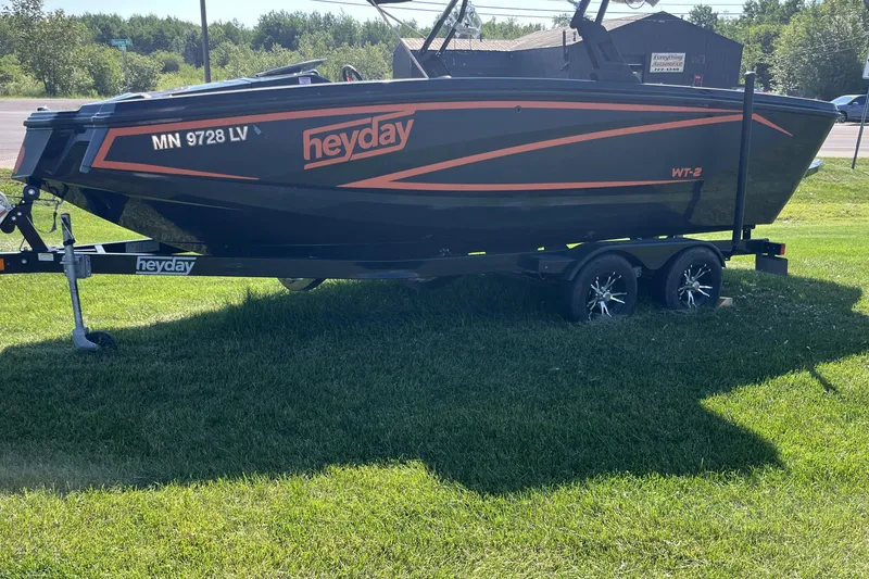 Slide: The Image of 2018 Heyday WT-2 boat on trailer, parked on grass, with orange accents. - 2