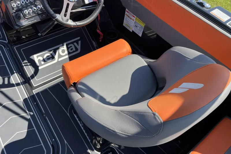 Slide: The Image of 2018 Heyday WT-2 boat interior with orange and gray seating, steering wheel, and control panel. - 13