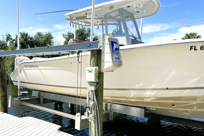 Slide: The Image of 2021 Cobia 280 Center Console boat docked on a lift by the water. - 17