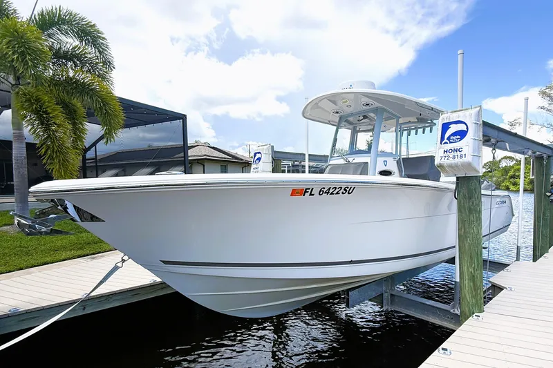 Slide: The Image of 2021 Cobia 280 Center Console boat docked near palm tree and waterfront home. - 19