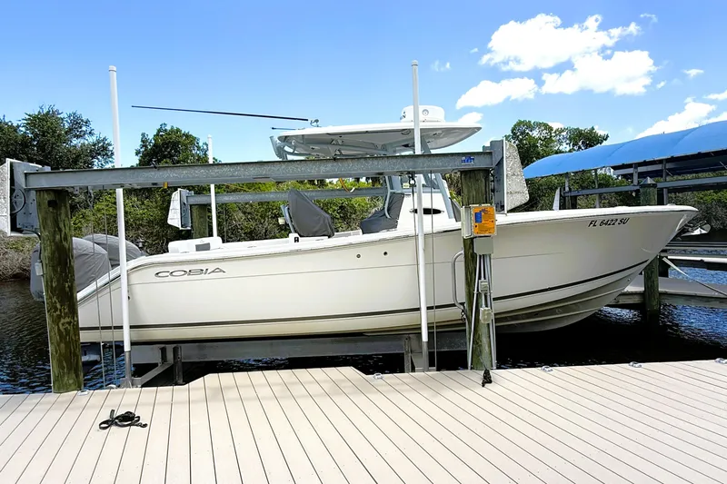 Slide: The Image of 2021 Cobia 280 Center Console boat docked on a lift, clear sky background. - 3