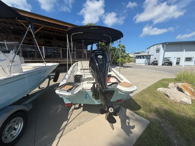 Slide: The Image of Boston Whaler 130 Super Sport 2027 with outboard motor, parked on a trailer outdoors. - 4