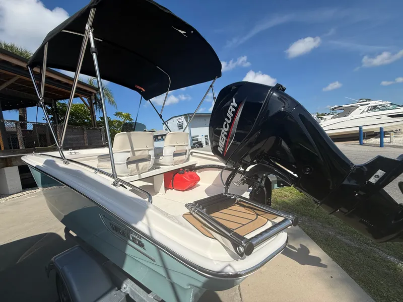 Slide: The Image of A 2027 Boston Whaler 130 Super Sport with a Mercury outboard motor, bimini top, and seating. - 16
