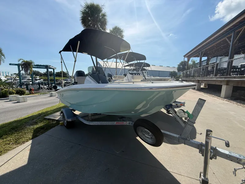 Slide: The Image of A 2027 Boston Whaler 130 Super Sport on a trailer under a blue sky. - 1