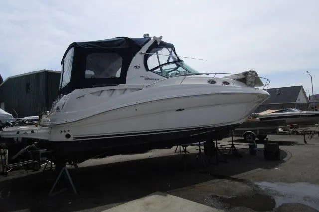 Slide: The Image of 2006 Sea Ray Sundancer 320 boat on dry dock, featuring sleek design and covered cockpit. - 2