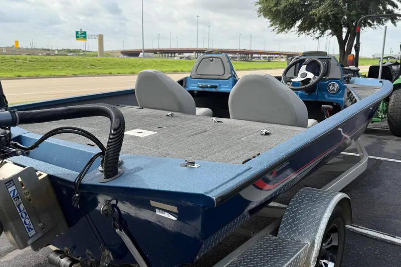 Slide: The Image of 2018 Xpress X19 Pro boat with dual seats and steering wheel, parked near highway. - 2