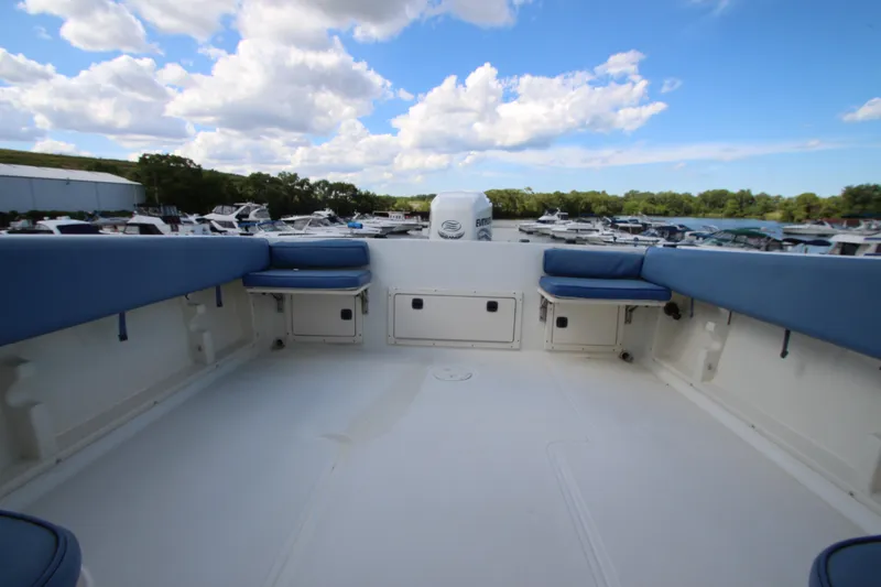 Slide: The Image of 2002 Hydra-Sports 230 WA boat interior with blue seating, docked at a marina under a cloudy sky. - 11